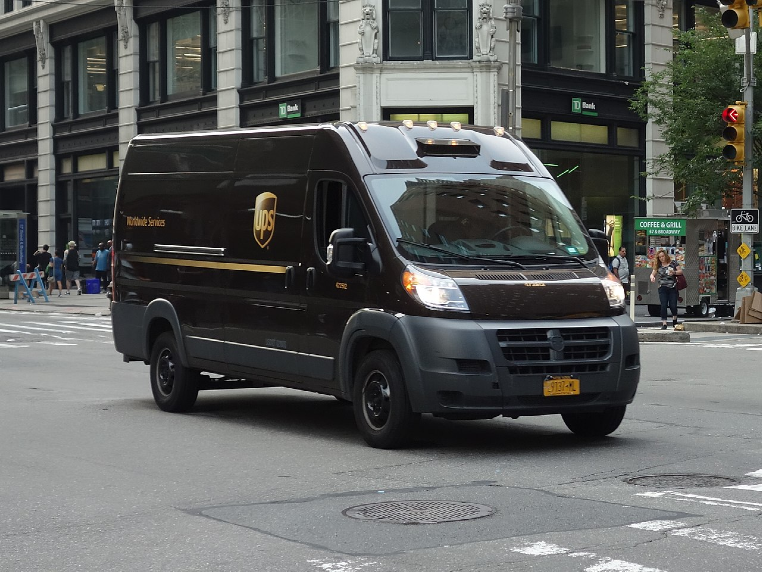 A brown UPS van with a golden yellow logo driving down a road.