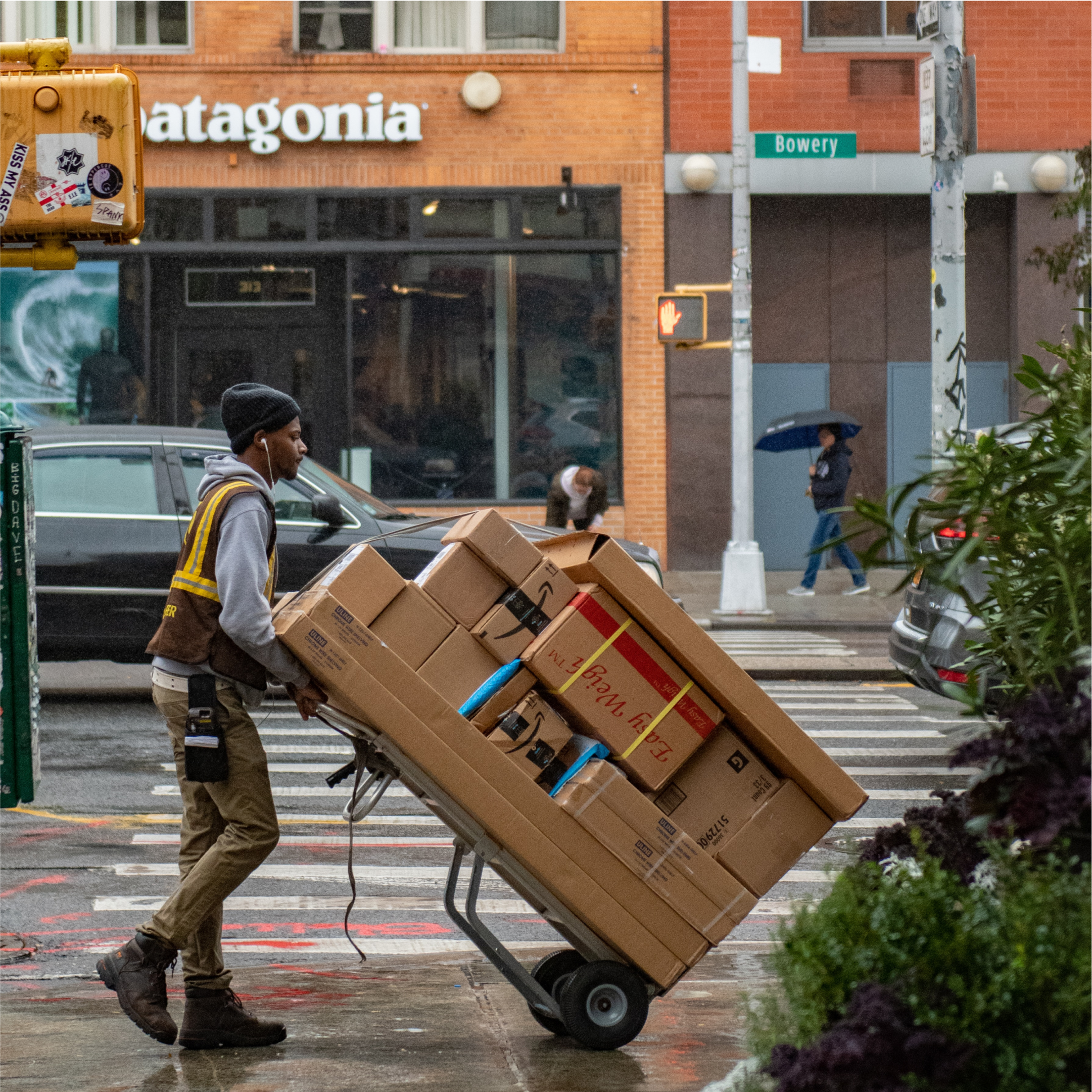 A UPS delivery man uses a crate lifter to wheel boxes down a street.